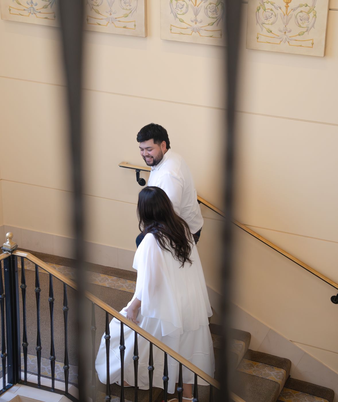 Gabe leading Nicky up a sweeping staircase