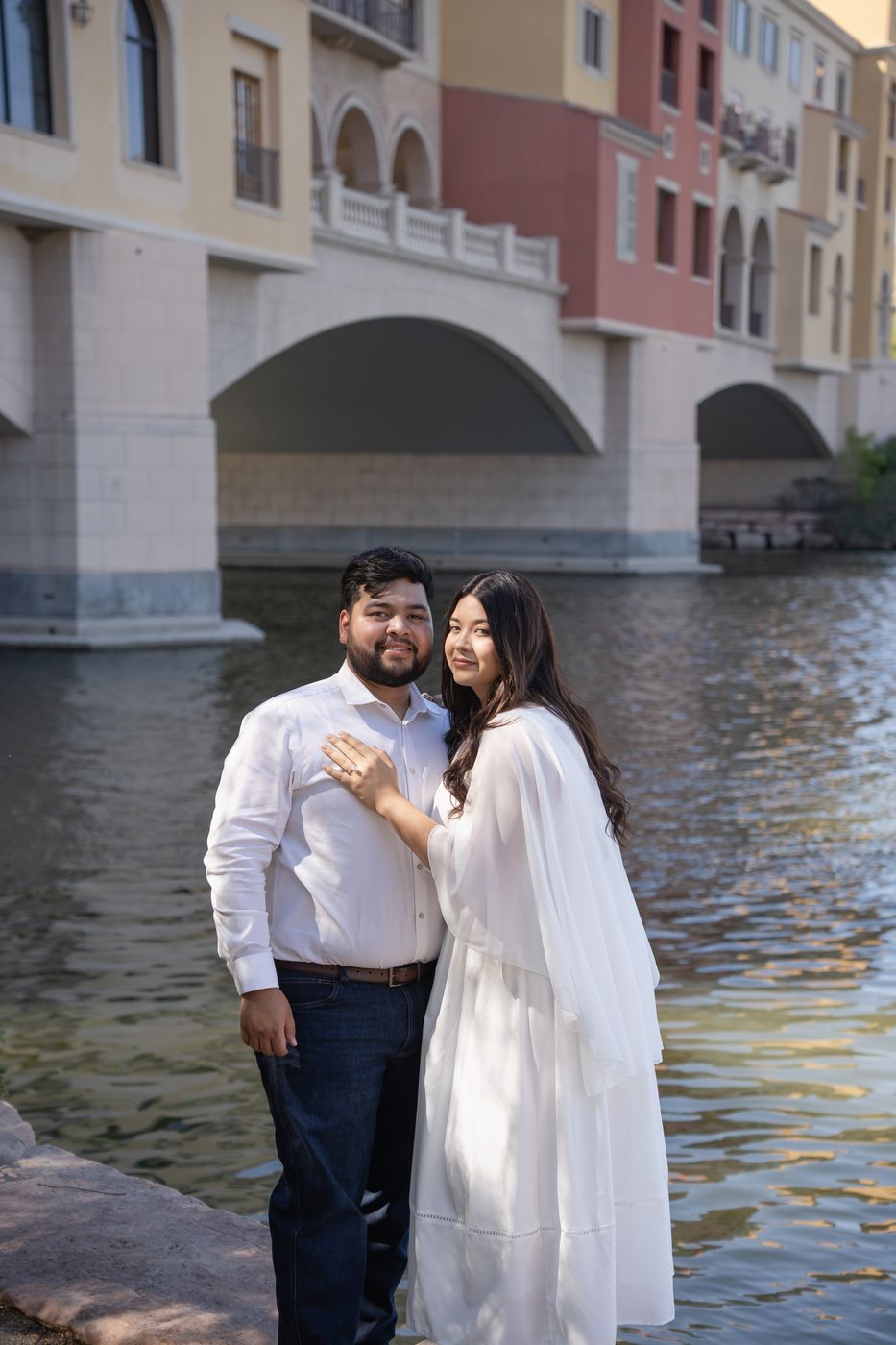 Nicky and Gabe by the water with arched bridges behind them